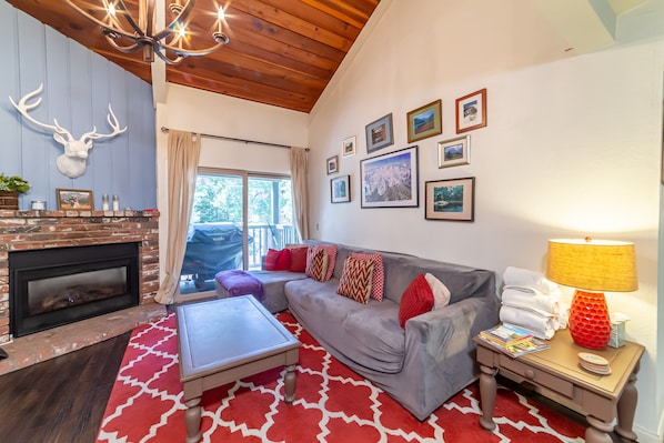 Open living room w/ gas burning fireplace and private deck.