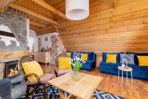 A wider angle of the living area, emphasizing the rustic mountain charm, natural light, and cozy seating arrangements.