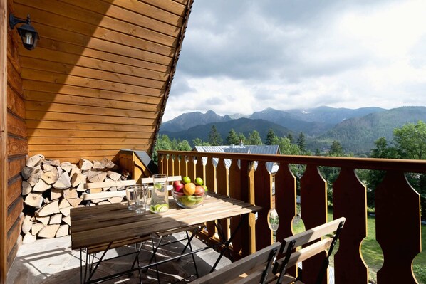 A charming wooden balcony with traditional mountain-style railings, offering stunning panoramic views of the surrounding peaks and valleys.