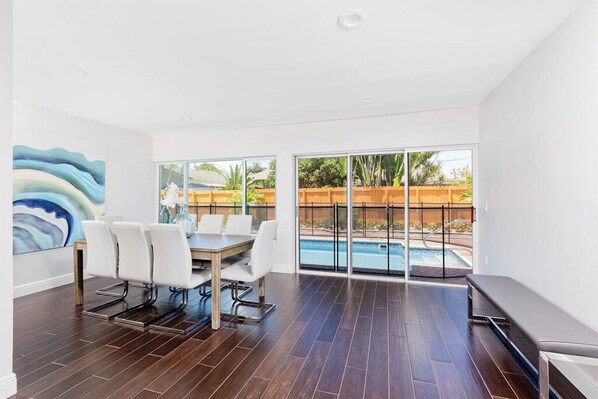 Elegant dining area with floor-to-ceiling windows offering stunning views of the sparkling pool. Perfect for enjoying meals while soaking in natural light and serene surroundings.