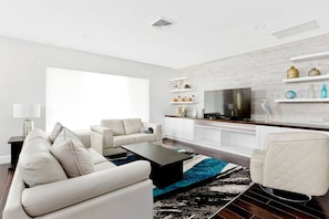 Bright and inviting living room with plush seating, a large-screen TV, and entertainment options—perfect for relaxing, catching up on your favorite shows, or enjoying sports games with your family and friends