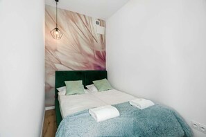A comfortable bedroom with a large bed, teal bedding, and artistic wall decor. The room is bright and calming, ideal for rest.