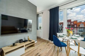 Another angle of the living room, highlighting a wall-mounted TV and the vibrant decor, with wooden flooring adding warmth to the design.