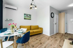 A combined living and dining area with an open layout. The dining table is set near the windows, creating a welcoming space.