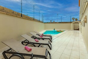 Heated private pool with comfortable sunbeds, back of the villa