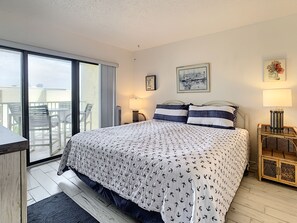 Bedroom with white and blue decorative cover on large bed with sliding door to patio