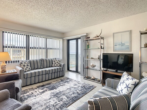 Living room with two couches and chairs with decorative rug.