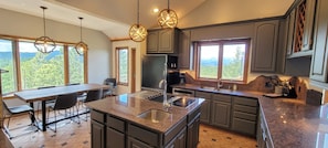 Full kitchen with JennAir cooktop, quartz countertops, and double ovens.
