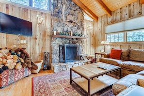 Living room with wood burning fireplace, TV, and comfortable furniture