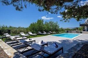 Pool area with deck chairs in the shade in the luxury family villa in Split 