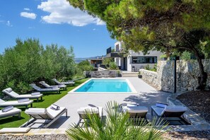 Pool area with deck chairs for relaxing on the sun of the vacation villa Yara in Kastela