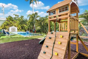 Spacious backyard with wooden playground, climbing wall and slide