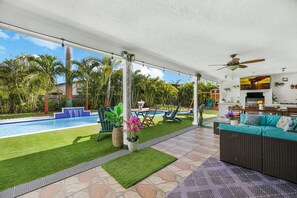 This backyard oasis features a sparkling pool, lush greenery & a spacious patio