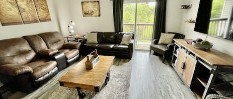 Family room with sleeper sofa and love seat and 55" smart TV in unit 5