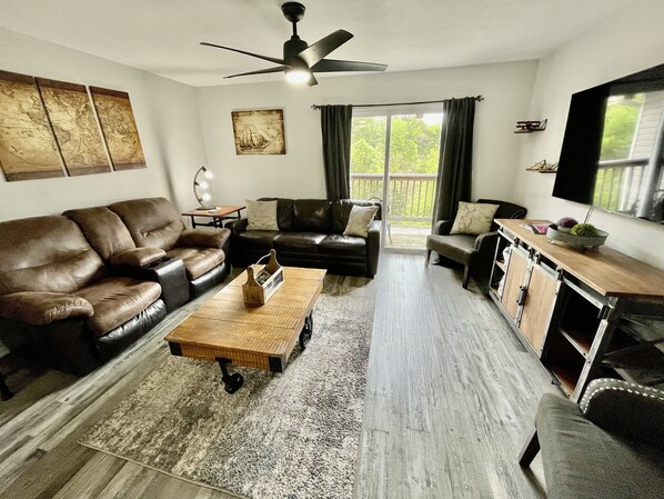 Family room with sleeper sofa and love seat and 55" smart TV in unit 5