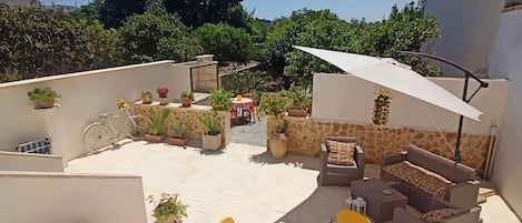 Patio e giardino con area relax, tavolo e barbecue in pietra
