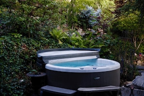 Book a time to unwind in the intimate shared hot tub surrounded by garden views 