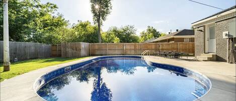 Private fenced backyard pool with lounge chairs 