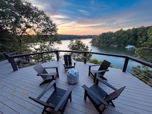 Large deck overlooking the lake with fire pit and Polywood Adirondack chairs.
