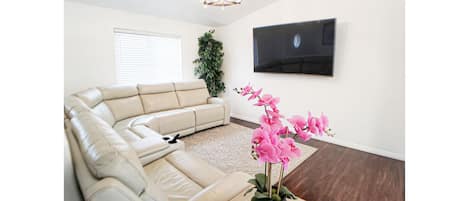 Large bright living room with leather power reclining sectional and 75 in HDTV!