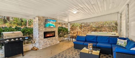 covered porch with electric fireplace, tv and hot tub