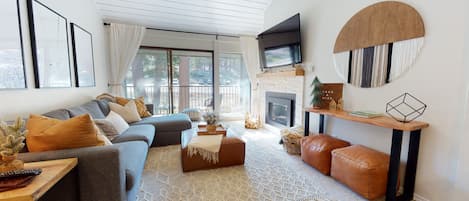 Living room with TV, gas fireplace, balcony access, and sofa sleeper