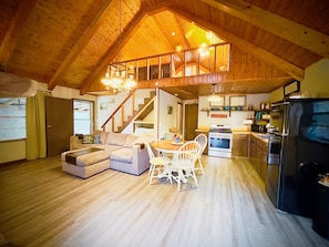Living area overlooking trout stream with LoveSac sofa, smart TV, kitchen, loft
