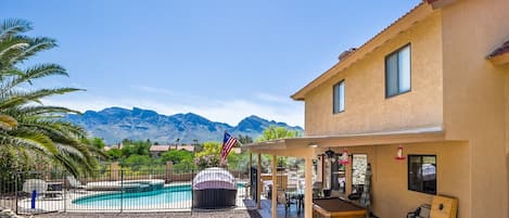 Backyard mountain view of pool, spa, pool table, and corn hole game.