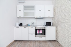 A white-themed kitchen with sleek cabinets, a microwave, and a built-in stovetop. The design is simple and functional.