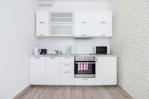 A white-themed kitchen with sleek cabinets, a microwave, and a built-in stovetop. The design is simple and functional.