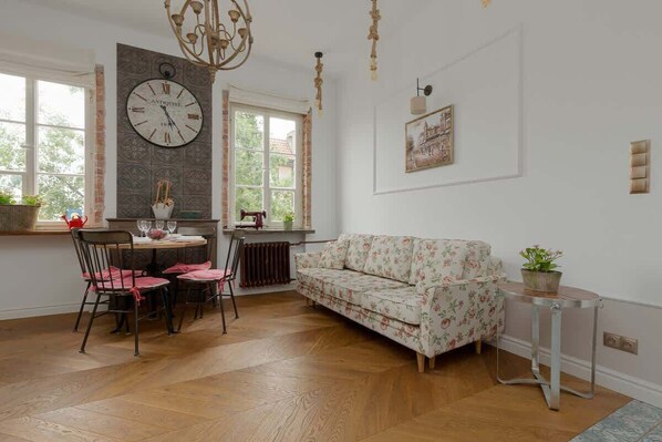 A cozy living room with a homely atmosphere, a soft sofa with floral patterns. The whole room is decorated in classic English style. The whole is complemented by tastefully selected accessories such as a large retro-style clock and table.
