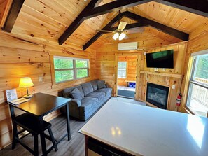 The main living space has a couch, TV, and gas fireplace with a table.