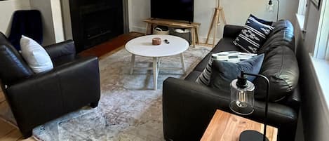 The living room has a leather couch, recliner, smart TV, and electric fireplace.