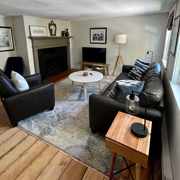 Living room with leather couch, recliner, smart TV, and electric fireplace.