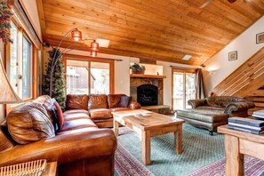 Cozy family room with indoor gas fireplace, comfortable seating, and flat-screen TV, with views and access to the outdoor patio