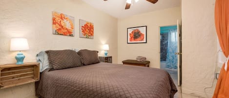 Bedroom with queen bed and ceiling fan. There is also a window a/c unit. 