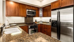 Another photo of the kitchen, displaying the fridge, oven range, and microwave.