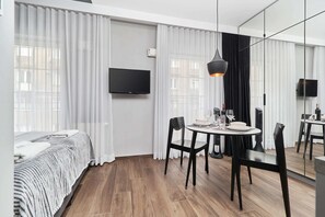 A bright dining area with large windows letting in natural light. The room has a mix of black and white furniture, adding to its modern aesthetic.