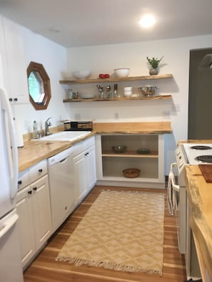 The renovated kitchen with live edge wood counters and open shelving 