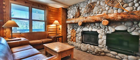 Feature river rock fireplace wall with flat screen TV and large log fireplace mantle