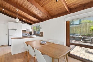 The Scandi dining table seats 6, with sliding doors opening onto the outdoor entertaining area. This huge deck has an outdoor dining setting and a Weber BBQ.