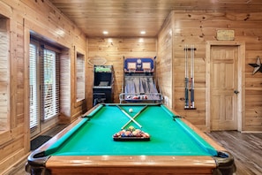 The game room is filled with a pool table, arcade, and a two-person basketball. 