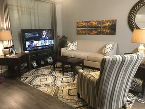 Living room with smart TV, comfortable chairs and modern couch. 