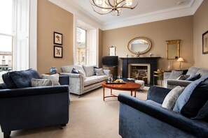 The Linen House - a light-filled drawing room with original slate fireplace, generous sofas and fine antiques
