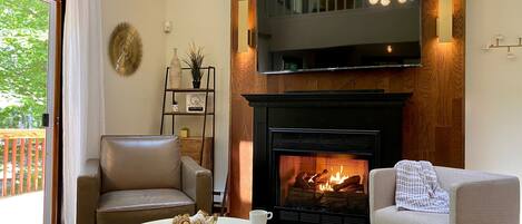 Cozy living room with a romantic gas fireplace and view of the forest.