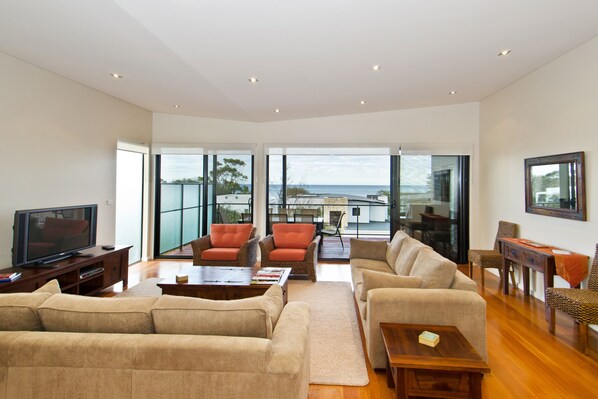 The top-floor living room offers comfort and connection, with plush seating, a large TV, and serene sea views.