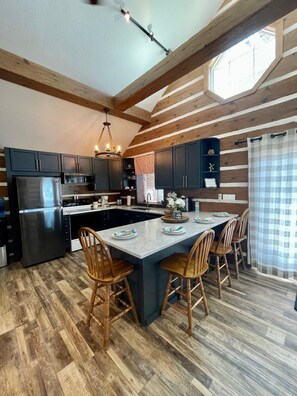 Kitchen features an island with dining for 4. Additional dining table is stored against the wall in the kitchen area to accommodate large groups.