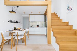 A compact kitchen area with a wooden dining table, surrounded by modern design and slanted ceilings.