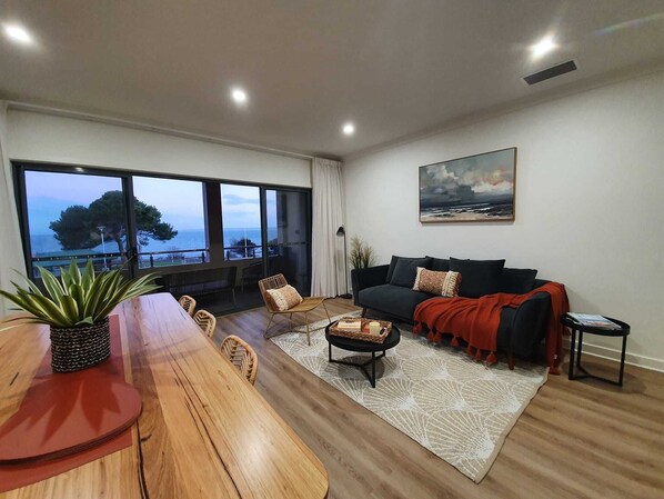 Mid-level open plan living, dining, kitchen, opens onto balcony with sofas