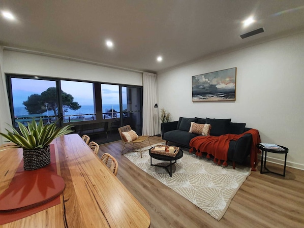 Mid-level open plan living, dining, kitchen, opens onto balcony with sofas